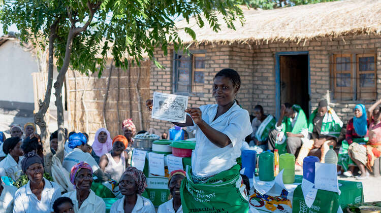 Eine Frau hält ein Plakat in der Hand und erklärt.