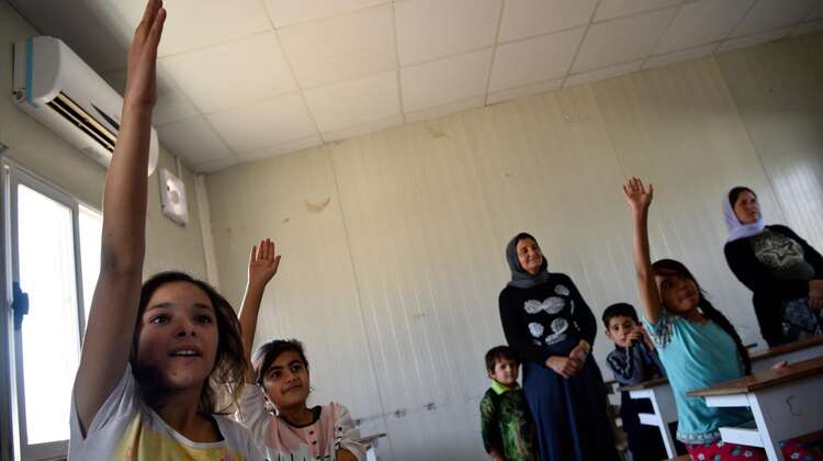 Schulkinder heben die Hand.