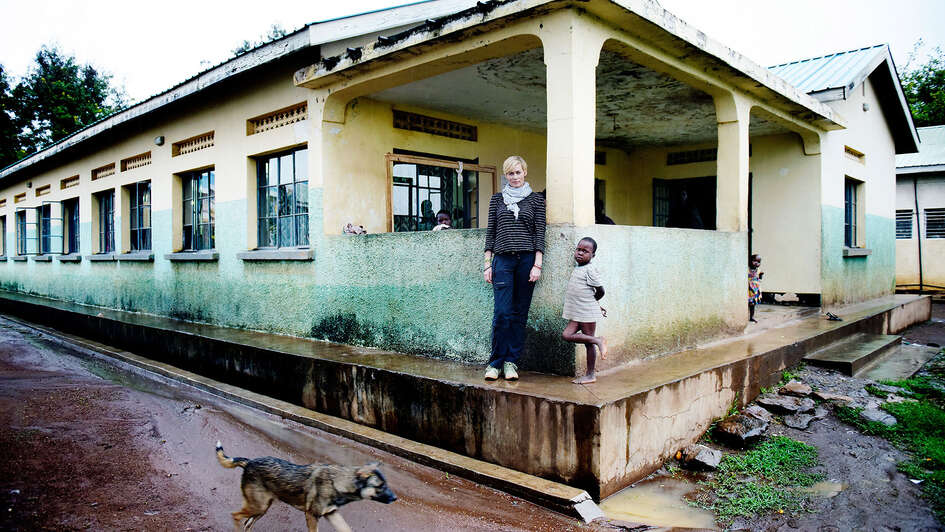 Schauspielerin Gesine Cukrowski mit einem kleinen Kind vor einem Krankenhaus in Uganda 