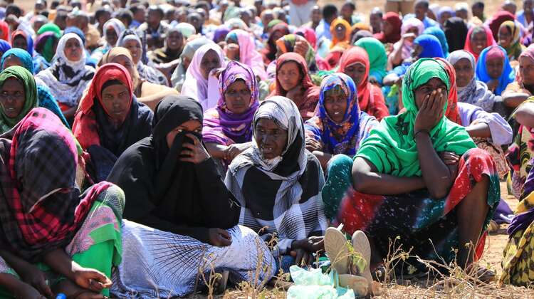 Eine große Gruppe Menschen wartet auf die Verteilung von Hilfspaketen.