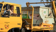 Ein Fahrer schaut aus dem Fenster eines LKW mit Müllcontainer.