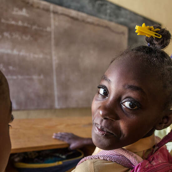 Ein afrikanisches Mädchen vor einer Schultafel.
