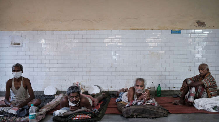 2020-coronavirus-slum-wanderarbeiter-delhi-indien-c-florain-lang.jpg Männer liegen auf Matratzen und schauen in die Kamera.