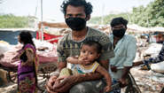 2020-coronavirus-slum-ranjeet-kumar-delhi-indien-c-florian-lang.jpg Ein Mann mit Mundschutz, er hält ein Baby auf dem Arm.