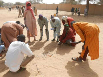 Mehrere Männer stehen und sitzen in einem Kreis.