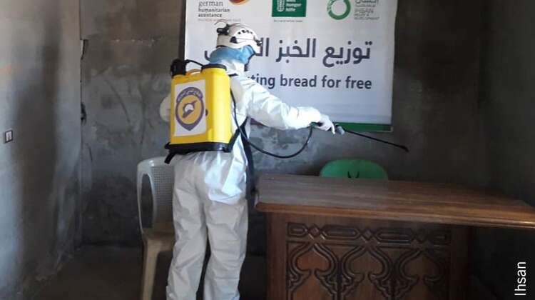 2020-lebensmittelverteilung-hygiene-corona-welthungerhilfe.jpg Eine Person in Schutzkleidung desinfiziert eine Verteilstätte für Brot
