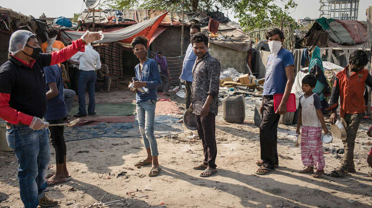 2020-coronavirus-slum-essensausgabe-schlange-delhi-indien-c-florian-lang.jpg Mehrere Menschen stehen in einer Schlange.