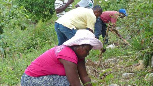 Bäuerinnen und Bauern bauen einen kleinen Steinwall zum Schutz gegen Erosion auf Haiti.