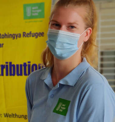 Eine Frau mit Mundschutz blickt in die Kamera.