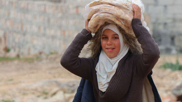 Ein junges syrisches Mädchen transportiert Brot auf ihrem Kopf 
