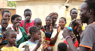 Junge Dorfbewohner applaudieren dem Musiker.