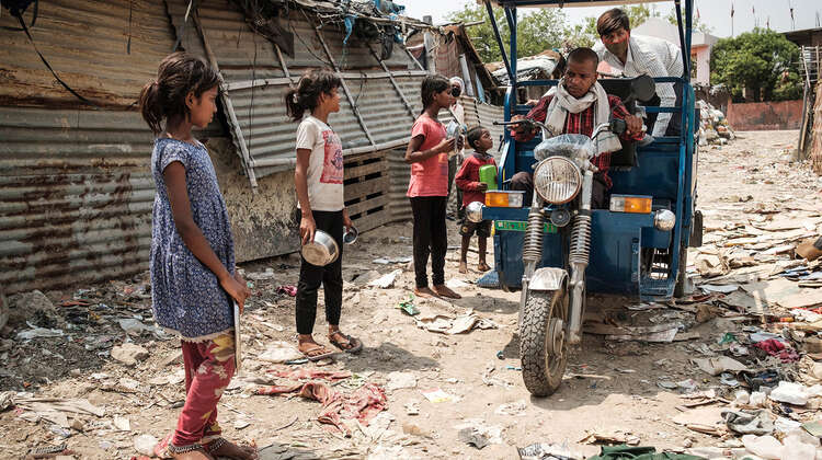 2020-coronavirus-obdachlosenunterkunft-essensausgabe-kinder-delhi-indien-c-florian-lang.jpg Kinder gehen mit leeren Schüsseln auf ein Riksha zu.