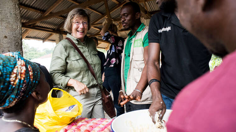 2019-marlehn-thieme-sierra-leone-schaukochen-lann_C_kai-loeffelbein.jpg Frauen und Männer lachen zusammen, man sieht eine Schüssel voller Essen.