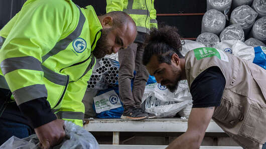 Drei Männer beladen einen LKW.