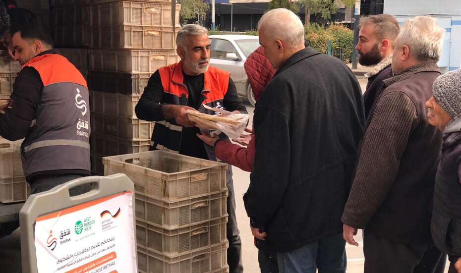 Hilfsarbeitende verteilen Brot an Menschen in der syrischen Region Aleppo