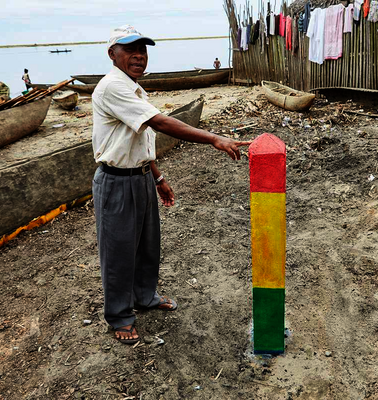 Ein Mann zeigt einen dreifarbigen Balken, der im Sand befestigt ist.