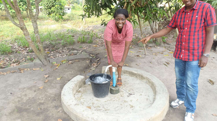 2021-sierra-leone-wasap-social-business-hand-drilled-well.jpg Eine Frau und ein Mann stehen an einer Wasserpumpe, Sierra Leone 2021.