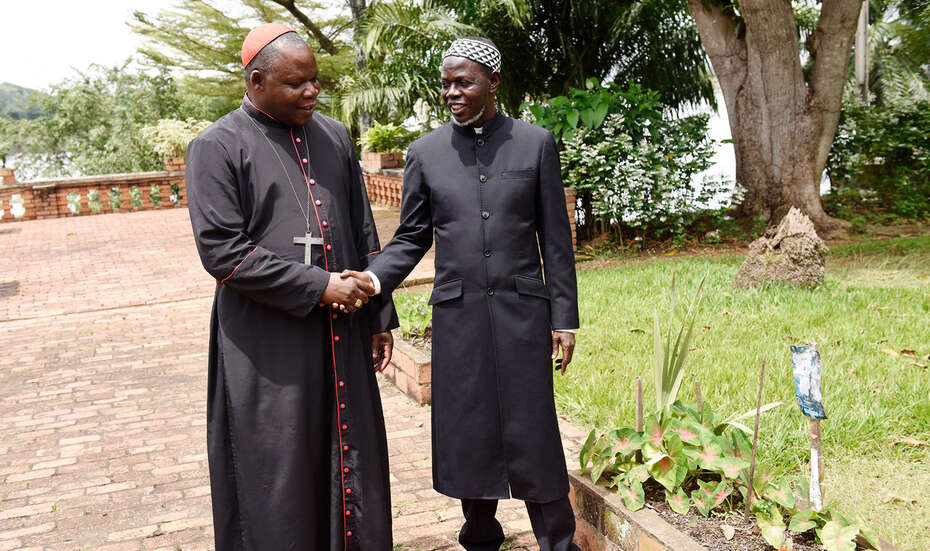 Zwei schwarz gekleidete Männer geben sich die Hand.