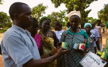 Patrick übergibt Saatgut an seine Schülerinnen.