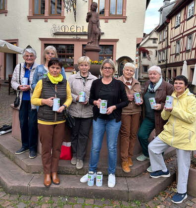 Gruppe von Frauen, die Spendendosen in der Hand halten und für Gruppenfoto in der Innenstadt posieren.