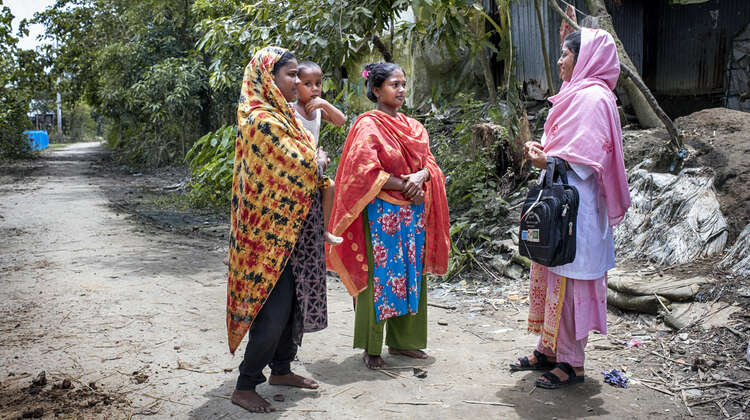 Ernährungsberarterin Ruby Akter unterhält sich mit zwei Frauen und einem Kind