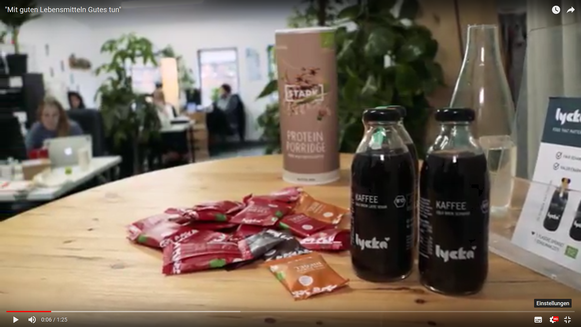 zwei Flaschen Lycka Kaffe stehen auf einem Holztisch. Im Hintergrund ist ein Café zu sehen.