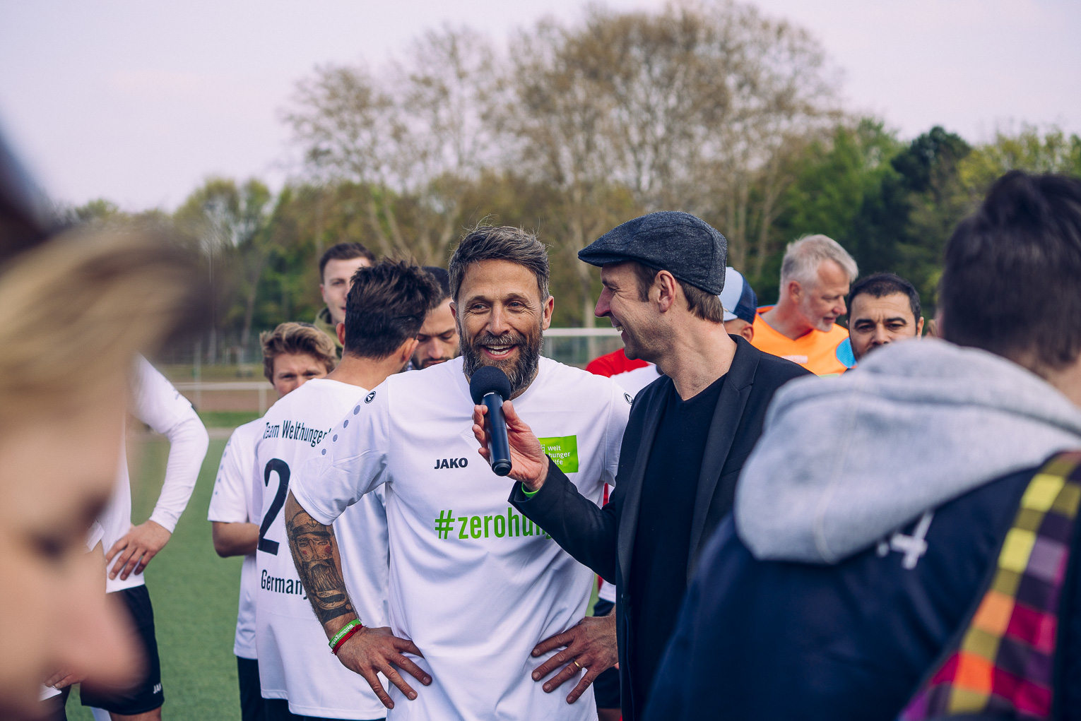 Florian Ambrosius in einem Fußballtrikot mit Aufschrift #zerohunger. Er wird interviewt.