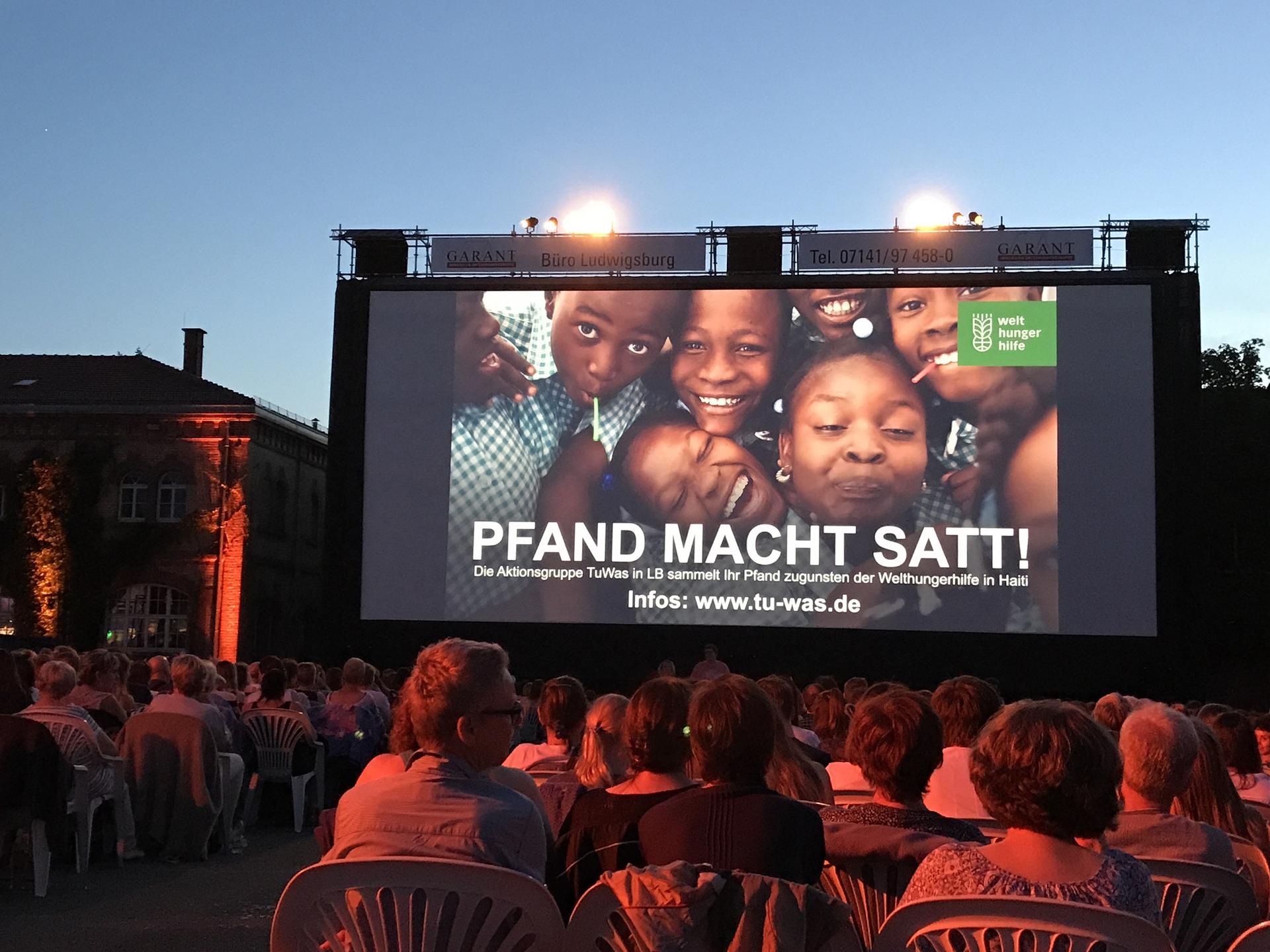 Publikum und Leinwand mit Werbung zu der Aktion "Pfand macht satt" 