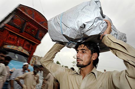 Ein Flüchtling transportiert seinen Besitz auf dem Kopf.