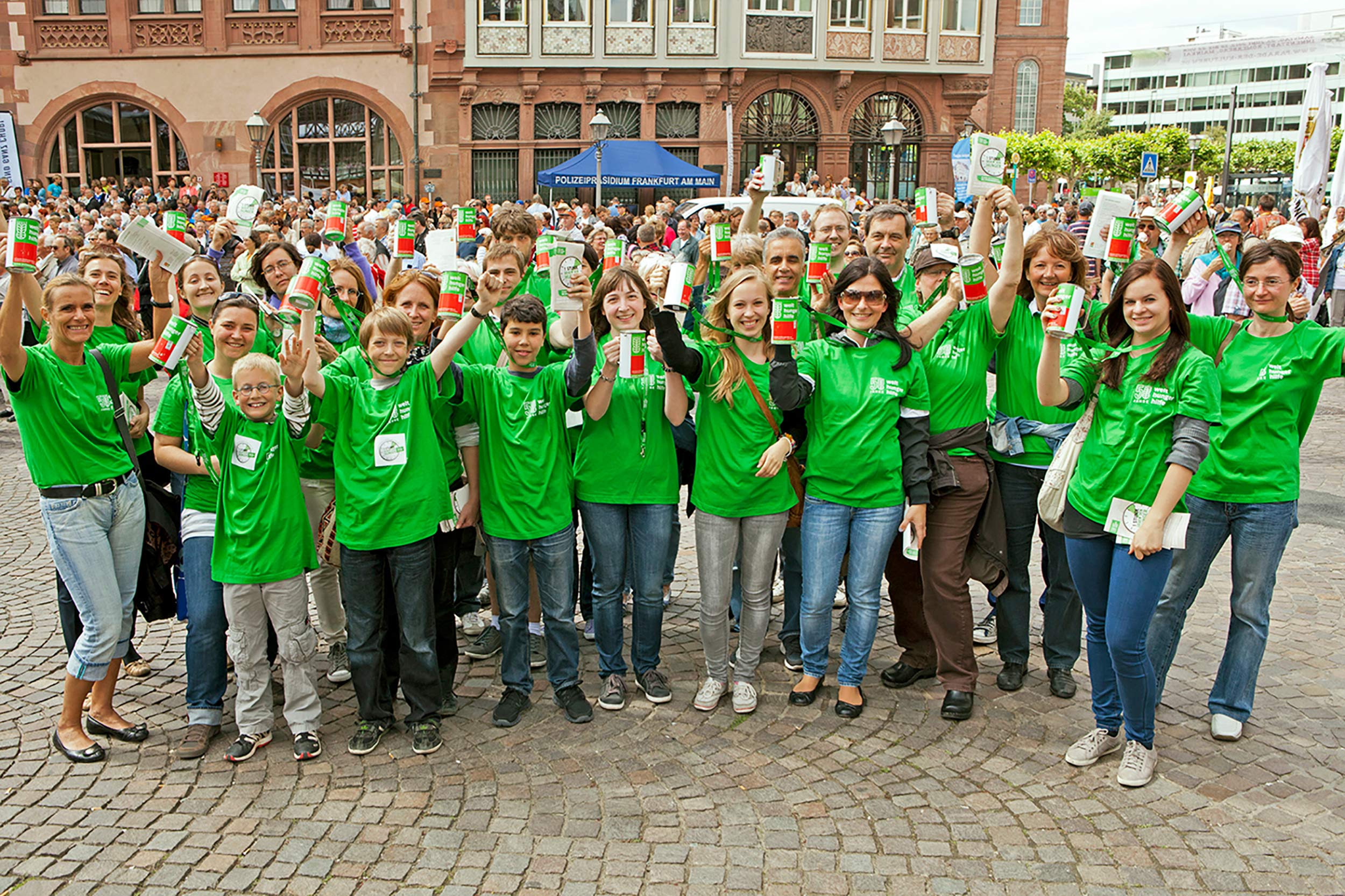 Menschen mit grünen T-Shirts schauen lachend in die Kamera.