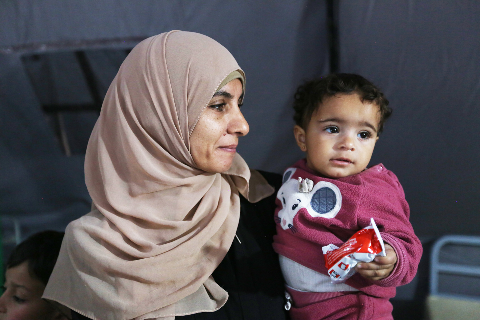 Eine Frau mit einem Kleinkind auf dem Arm, Gaza