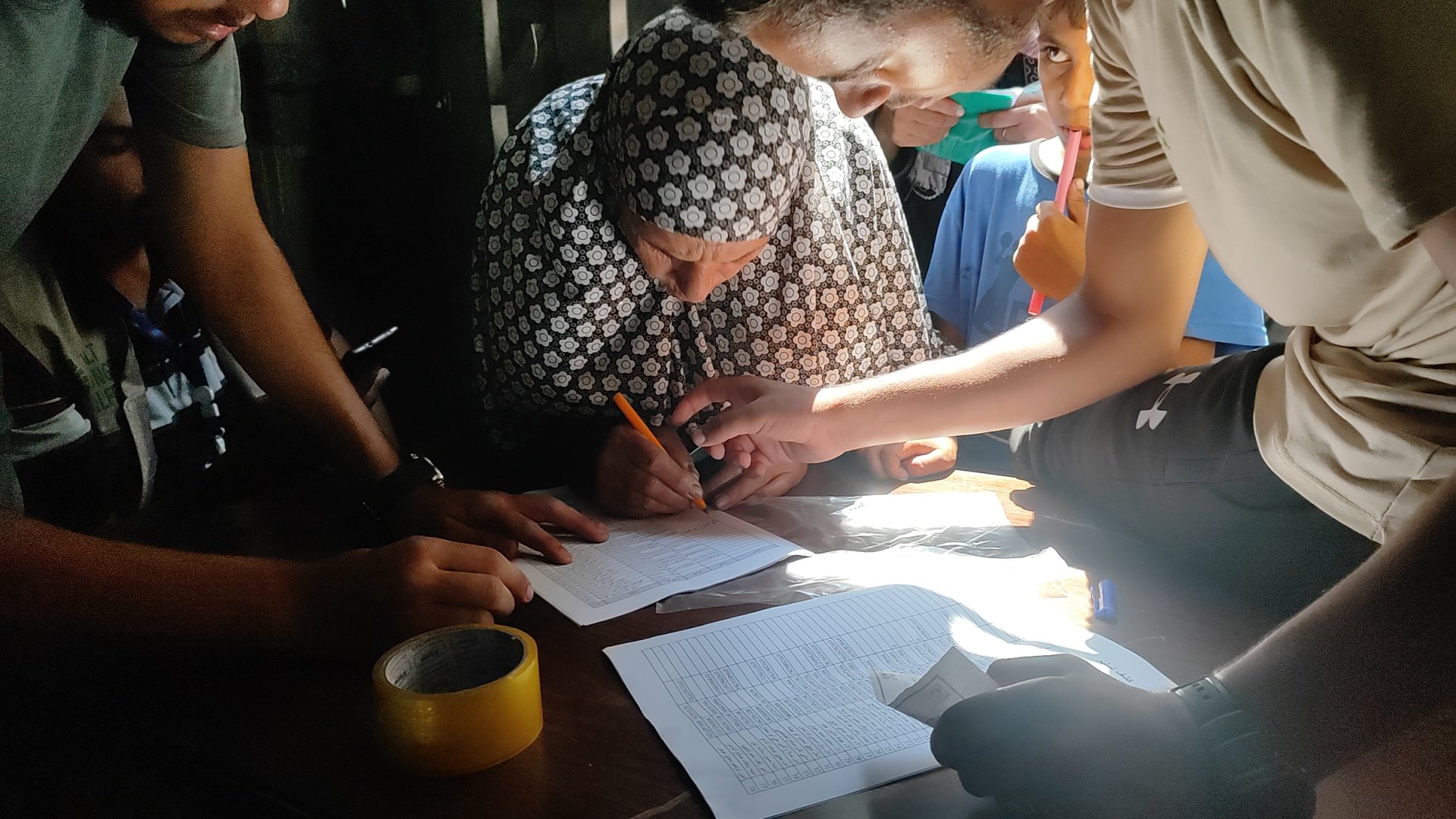 Eine Frau unterschreibt Dokumente bei der Verteilung von Hilfsgütern im Gazastreifen