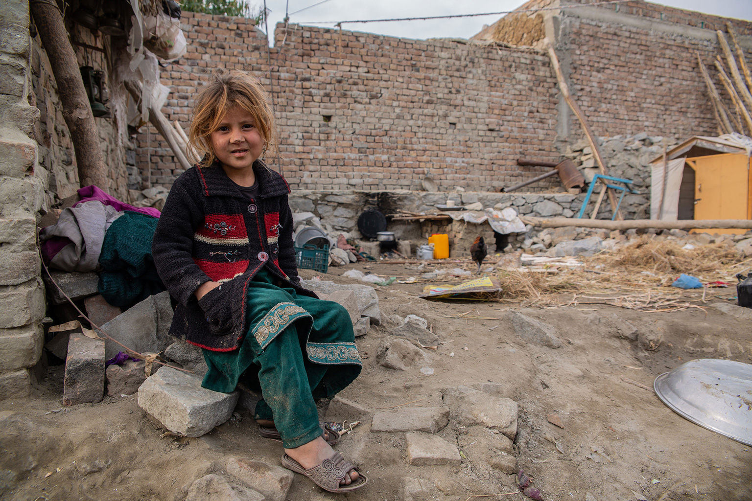 Mädchen sitzt vor Trümmern in Afghanistan