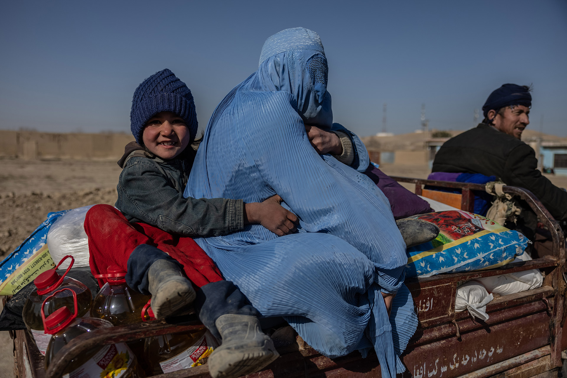 Ein Mädchen sitzt mit ihrer Mutter auf der Ladefläche eines Wagens, Afghanistan 2022.