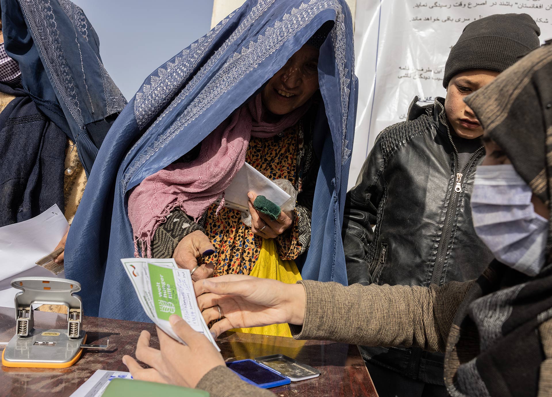 Eine Frau lächelt und nimmt ein Registrierungsausweis entgegen.