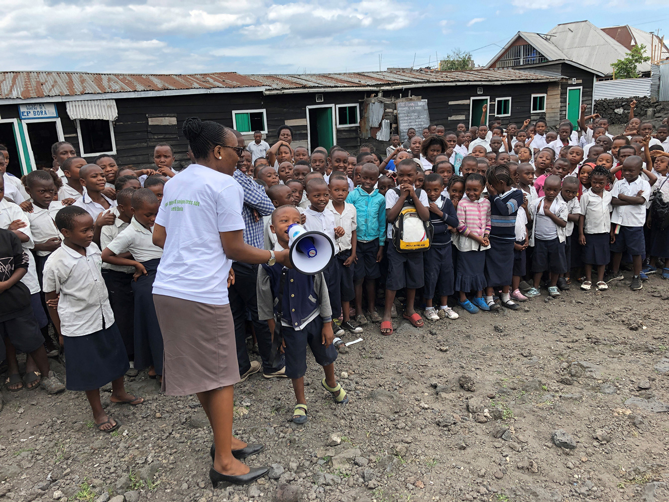 Ein Schüler sagt etwas durch ein Megafon, im Hintergrund viele weitere Schüler.