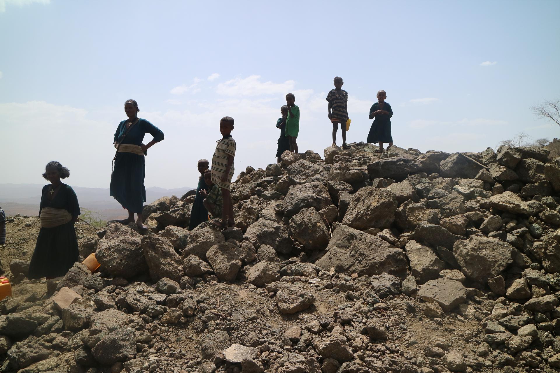 Menschen stehen auf einem Berg ausgetrockneter Erde.