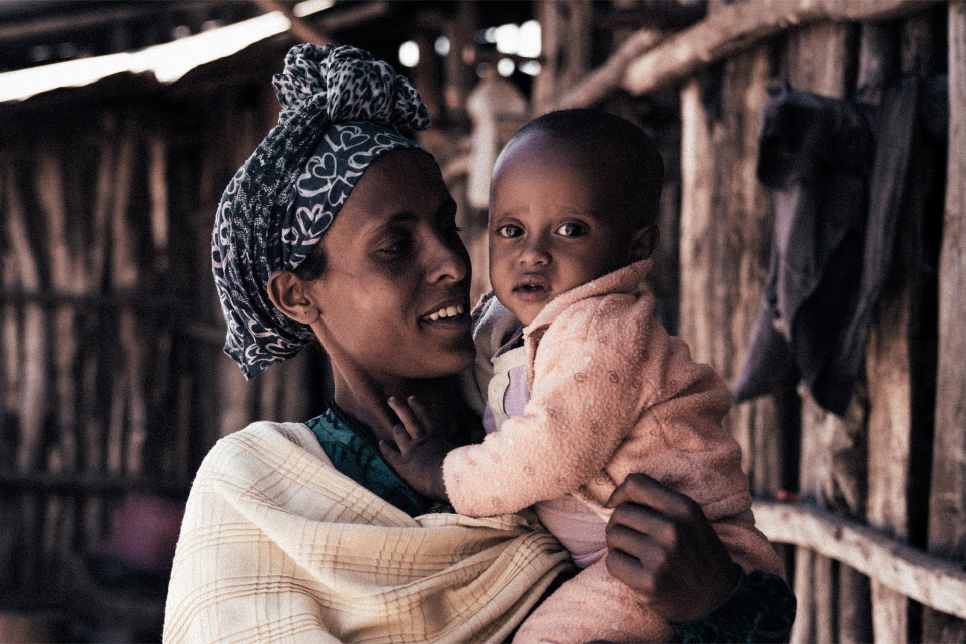 Eine Frau hält ein Baby im Arm und lächelt.