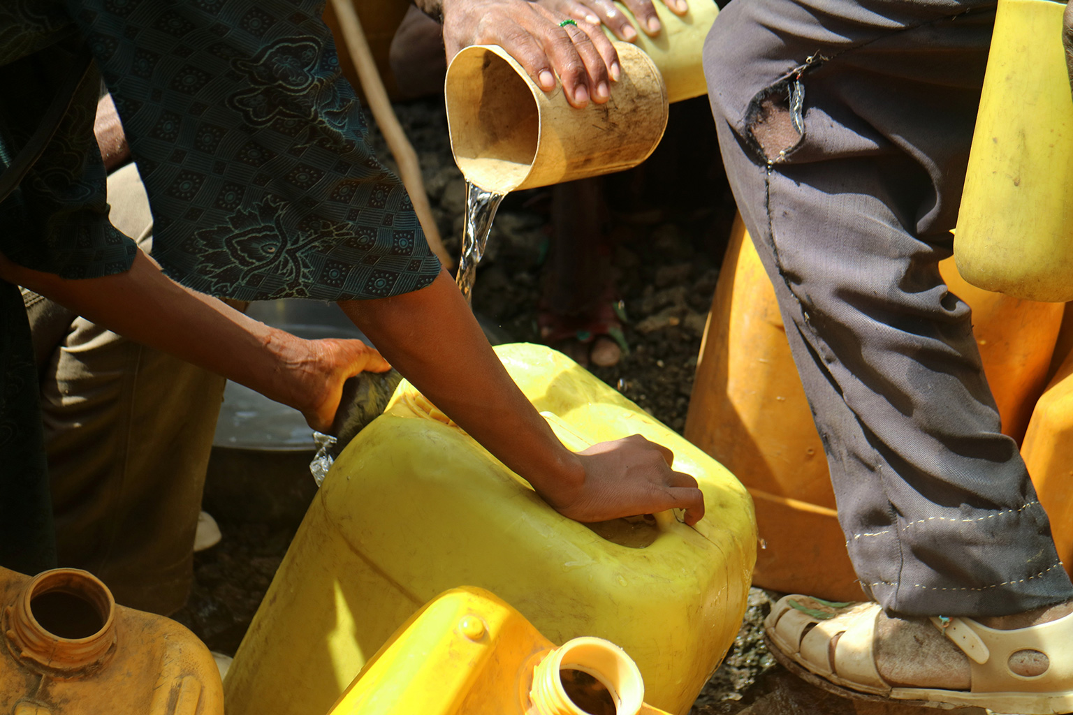 Menschen befüllen gelbe Kanister mit Wasser