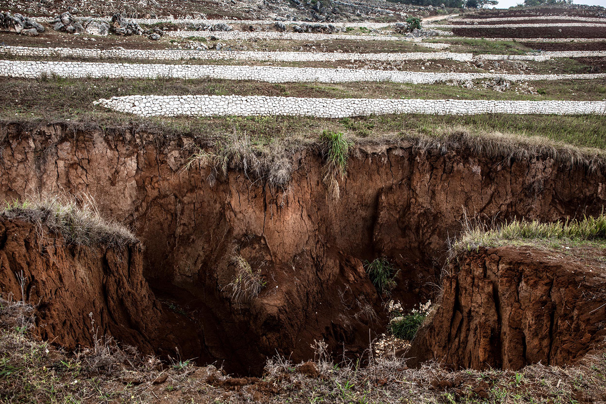 Ein kraterartiges Loch in der Erde. Im Hintergrund sieht man weiße Schutzwälle.