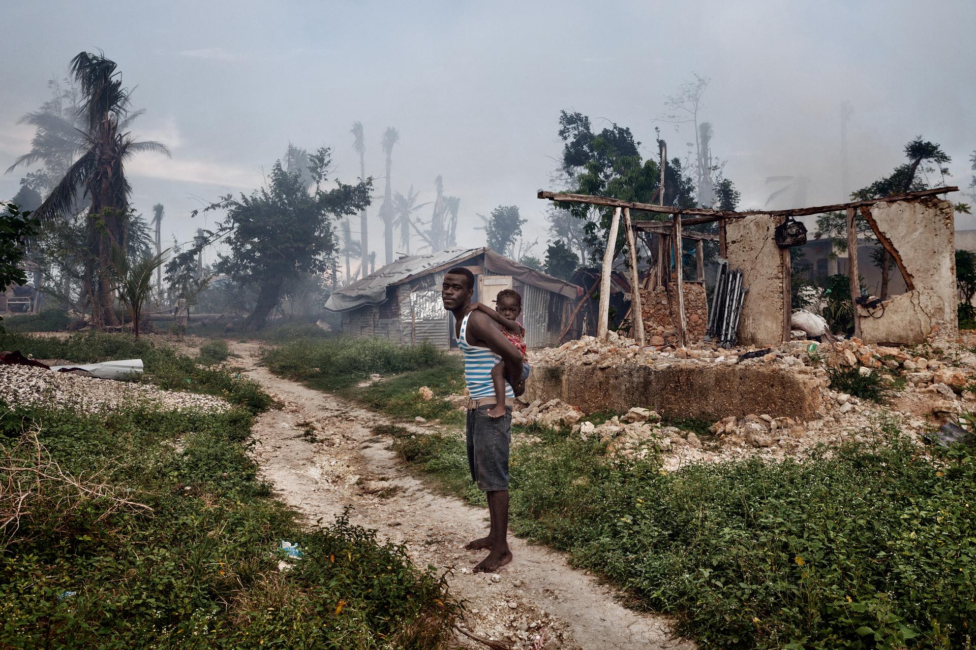 Ein Mann mit seiner Tochter vor den Ruinen eines Hauses in Grand Anse.