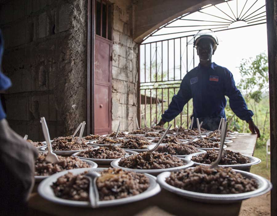 zwei Männer tragen eine Platte mit gefüllten Tellern aus dem Haus