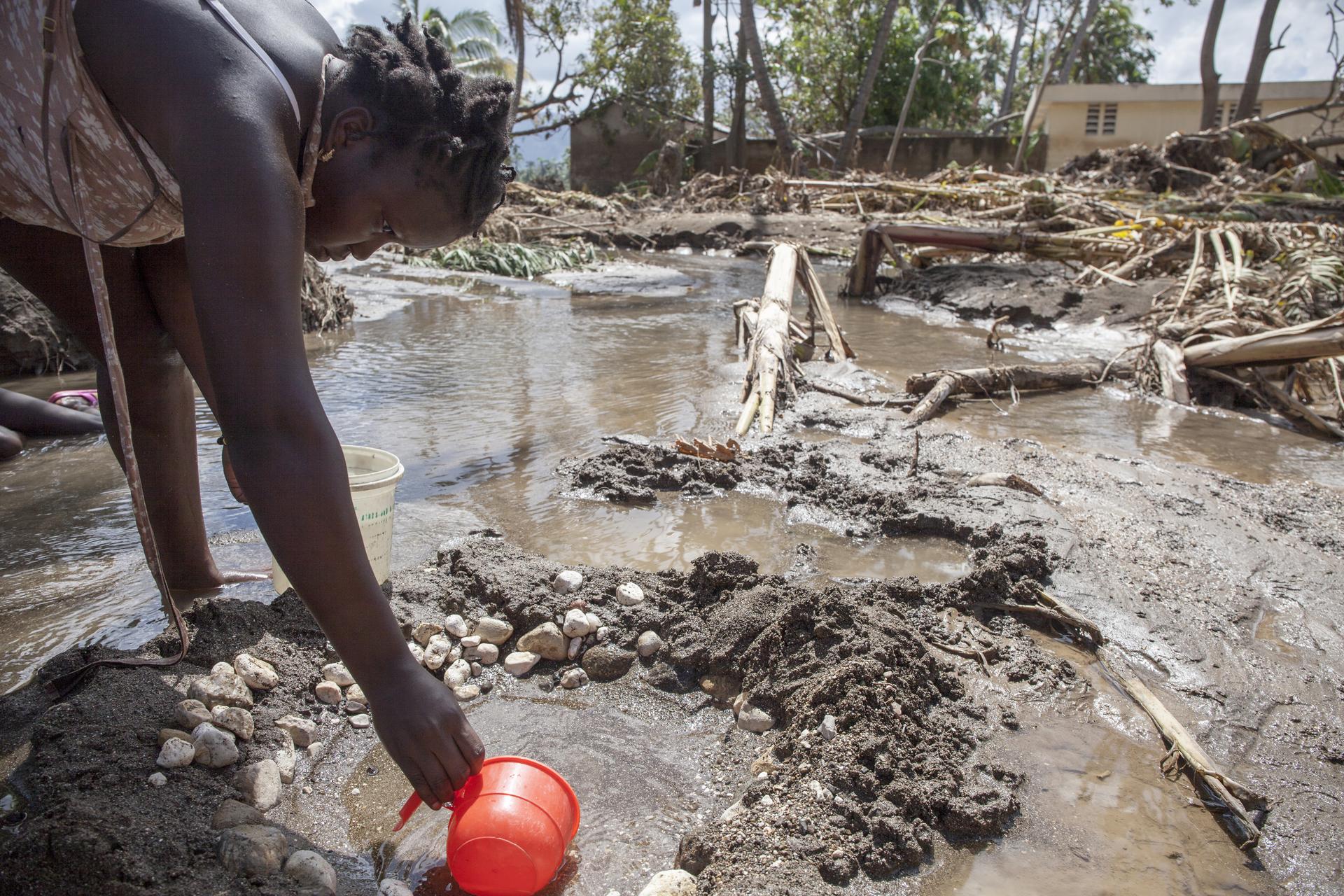 Wetterextreme treffen oft die Ärmsten - Eine Frau schöpft Wasser nach Hurrikan Mathew in Haiti.