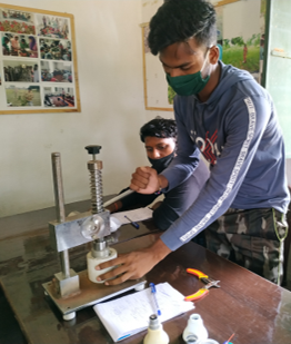 Ein junger Mann repariert eine LED-Glüchbirne, Indien 2021.