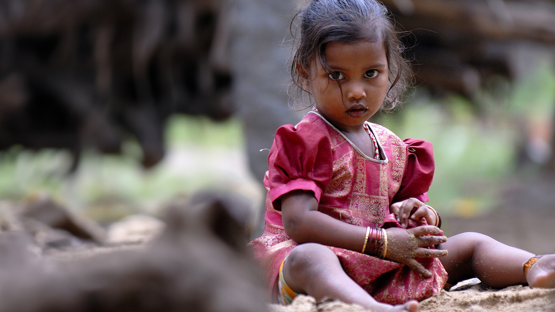 Kleinkind sitzt auf dem Boden und schaut in die Kamera