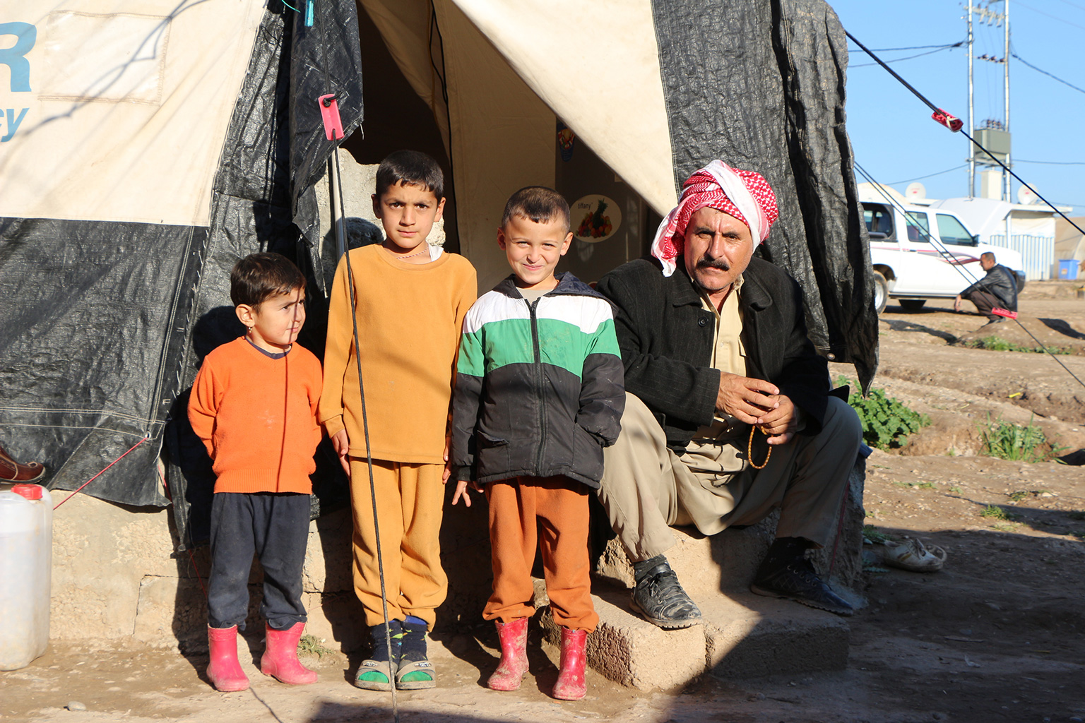 Familie sitzt vor ihrem Zelt