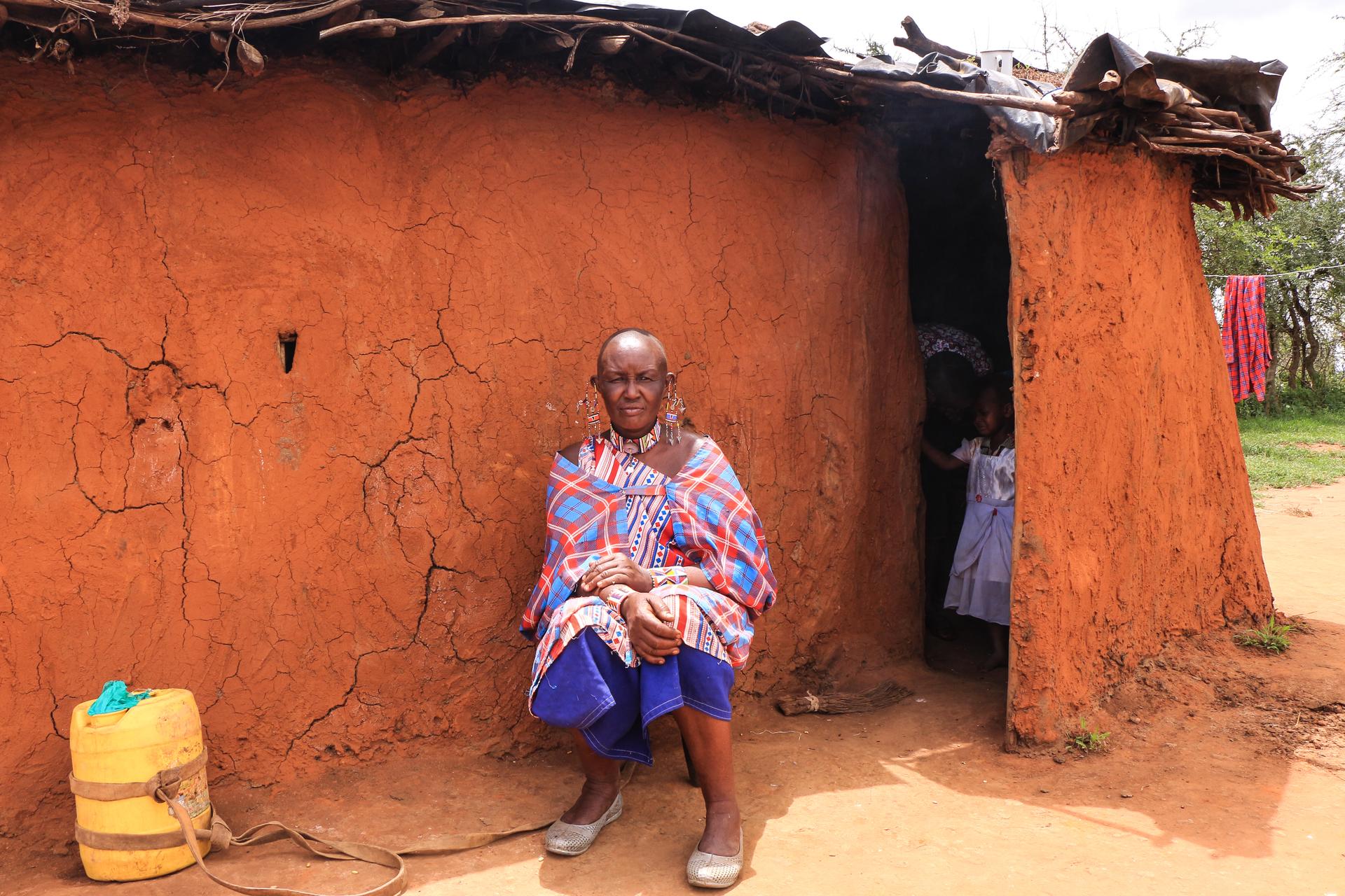 Massai Esther Sululi Makooi vor einer Hütte.
