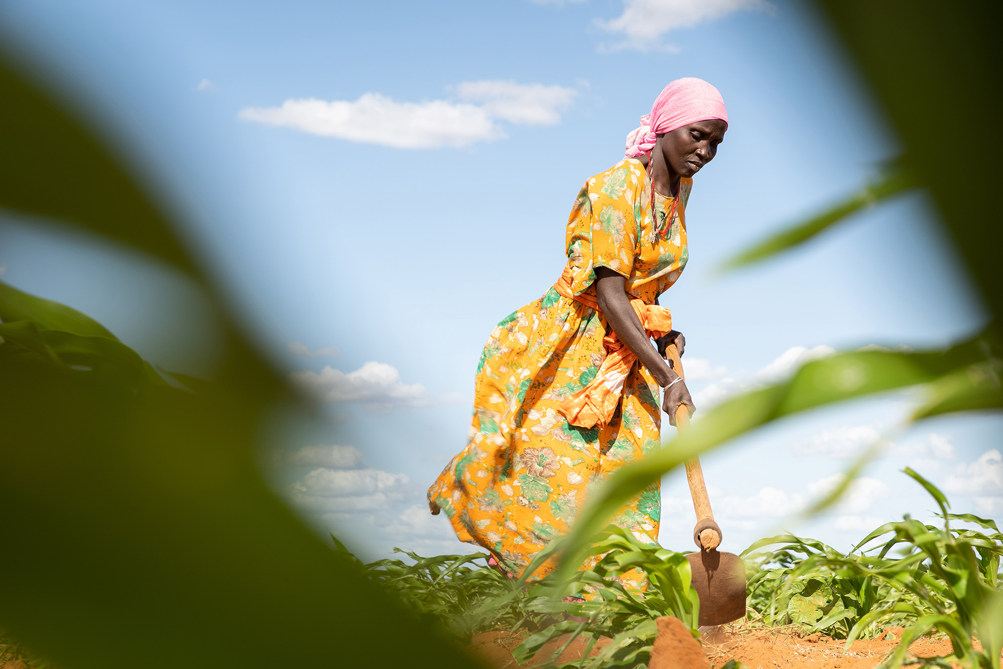 Eine Frau in Kenia beackert mit einer Hacke ein Feld.