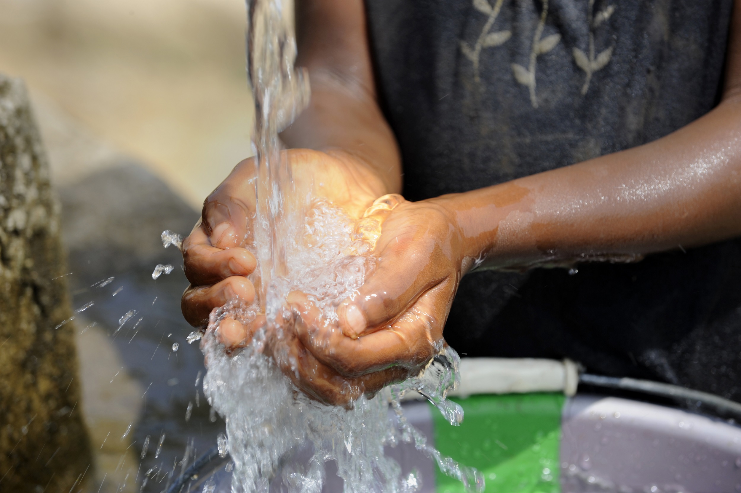 Zugang zu Wasser: Hände schöpfen Wasser unter einem Wasserstrahl.
