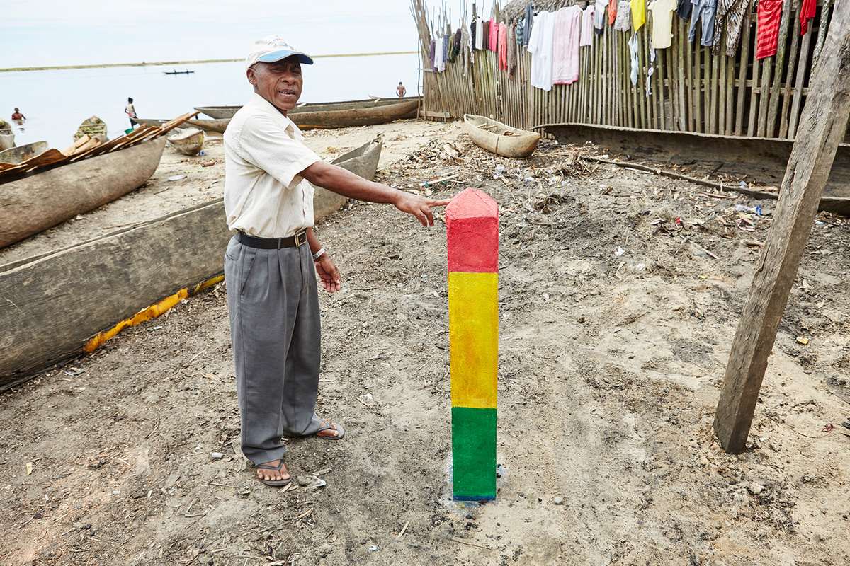 Ein Mann zeigt einen dreifarbigen Balken, der im Sand befestigt ist.